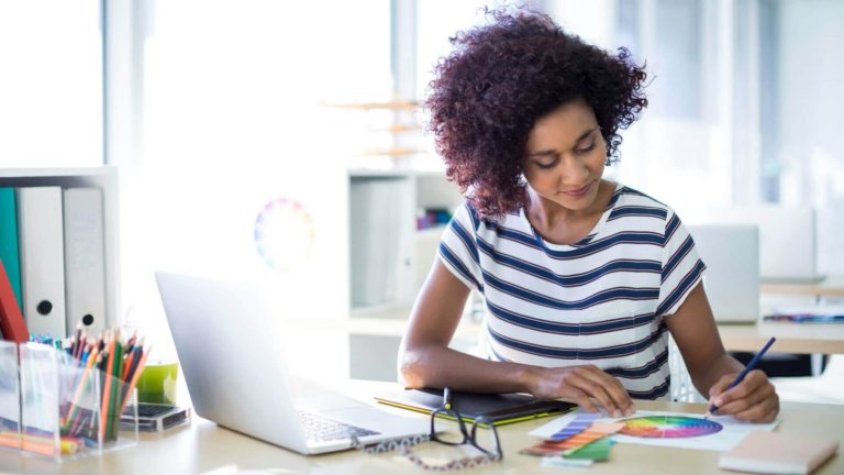 Mulher sentada à mesa com um notebook aberto e trabalhando sozinha simulando uma pessoa introvertida