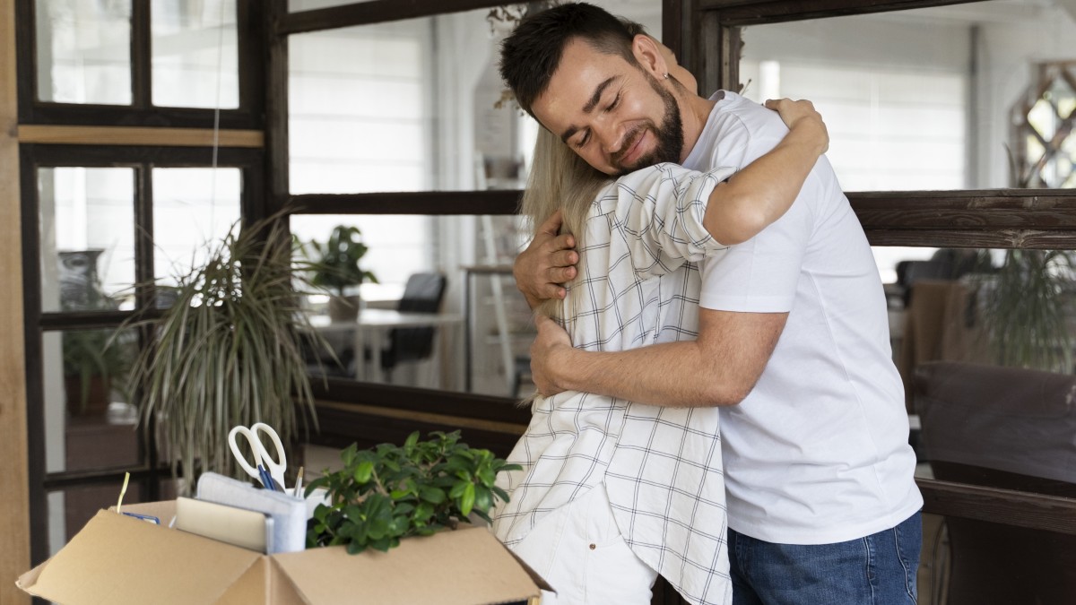 Uma mulher e um homem se abraçando, uma caixa com itens pessoais dentro para simbolizar o offboarding humanizado