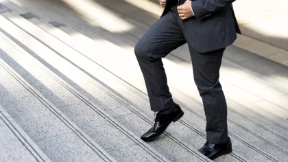 Homem execuivo, vestido com terno e sapatos sociais subindo uma escadaria , transmitindo determinação e profissionalismo